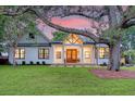 Charming home with a spacious lawn, inviting entrance, and warm lighting at dusk at 422 Palm St, Mount Pleasant, SC 29464