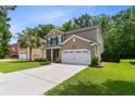 Well-maintained two-story home with a spacious driveway, a two-car garage, and lush green landscaping at 5451 Kings River Dr, North Charleston, SC 29420