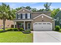 Beautiful two-story home featuring a manicured lawn, a two-car garage, and a cozy front porch with red seating at 5451 Kings River Dr, North Charleston, SC 29420