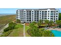 Exterior view of the condo building featuring multiple balconies, beach access, and tropical landscaping at 8000 Palmetto Dr # 104-A, Isle of Palms, SC 29451