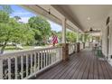 Spacious front porch with wooden flooring, classic white railings, brick supports, and views of the neighborhood at 115 S Ainsdale Dr, Charleston, SC 29414