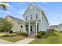 Charming two-story home with a covered front porch featuring rocking chairs and lush landscaping at 308 Watergrass St, Summerville, SC 29486