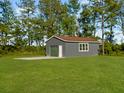 A detached gray one-car garage with a concrete drive sits amid green lawn and mature trees at 341 Sugar Hill Rd, Saint George, SC 29477
