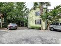 Side view of light green home with a gravel driveway and partial view of both parked vehicles at 3.5 Kracke St # C, Charleston, SC 29403