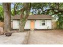 Exterior view of a cozy home with an inviting orange door, light shutters, and mature trees at 5037 Alpha St, North Charleston, SC 29405