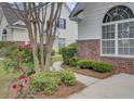 Close up of house showing brick accents, landscaped yard, and an arched window with lots of natural light at 5223 Fernland Way, Charleston, SC 29420
