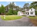 Beautiful property with a charming white home, detached garage, and a long gravel driveway at 6373 Farm House Rd, Ravenel, SC 29470