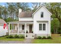 Charming two-story white home with a welcoming front porch and lush landscaping at 6373 Farm House Rd, Ravenel, SC 29470