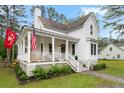 Inviting white home with a classic porch, string lights, and neat landscaping at 6373 Farm House Rd, Ravenel, SC 29470