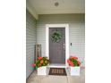 A welcoming front door with a decorative wreath, flanked by vibrant flower pots and a 'Cook Well' sign at 107 Belgian Ct, Summerville, SC 29486