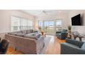 Bright living room featuring a large gray sofa, hardwood floors, and a balcony with seating at 126 W 2Nd St, Folly Beach, SC 29439