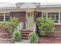 Inviting home entrance with brick steps, white railing, green door, and vibrant landscaping at 1534 Salisbury St, Charleston, SC 29407