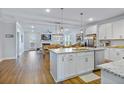 Bright, open-concept kitchen and living space with white cabinets, island seating, and hardwood flooring at 179 Darby Meadow Ln, Ridgeville, SC 29472
