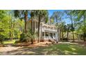Elegant two-story home with a double porch, surrounded by lush greenery and mature palm trees at 2225 Black Oak Court, Mount Pleasant, SC 29466