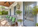 Cozy front porch with rocking chairs, green cushions, and decorative lantern at 225 Delahow St, Daniel Island, SC 29492
