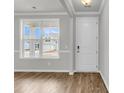 Bright living room with wood floors, large window, and freshly painted white door and walls at 319 Abercom Place Dr, Moncks Corner, SC 29461