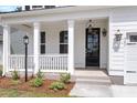 Inviting front porch with white columns, a black front door, and landscaped flowerbeds at 389 Wappoo Trace Ln, Summerville, SC 29486