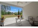 Covered patio with fan, table, and chairs overlooking a lush, private backyard at 423 Four Seasons Blvd, Summerville, SC 29486
