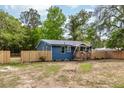 Cozy blue house with a metal roof and wooden fence surrounded by lush trees at 6146 Chisolm Rd, Johns Island, SC 29455