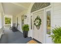 Inviting front porch with rocking chairs, ferns, and an elegant door with decorative wreath at 1 Bay Ct, Isle of Palms, SC 29451