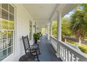 Spacious covered front porch with rocking chair and elegant white railings, perfect for relaxing outdoors at 1 Bay Ct, Isle of Palms, SC 29451