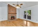 Bright living room featuring a brick fireplace, hardwood floors, and large windows for natural light at 106 Chaff Ct, Summerville, SC 29485