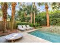 Private backyard pool with lush landscaping, lounge chairs, and a serene water feature at 108 Carolina Blvd, Isle of Palms, SC 29451