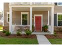 Inviting front porch featuring a cozy bench, red door, and well-maintained landscaping at 1417 Roustabout Way, Charleston, SC 29414