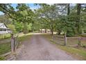 View of an unpaved driveway leading to a home with a wood fence, lush trees, and open skies at 158 Whippoorwill Dr, Summerville, SC 29483