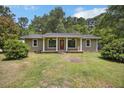 Inviting one-story home featuring a red front door with white columns, complemented by a verdant front yard at 158 Whippoorwill Dr, Summerville, SC 29483