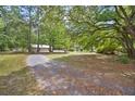 Scenic view of a gravel driveway leading through a spacious yard with mature trees and open skies at 158 Whippoorwill Dr, Summerville, SC 29483