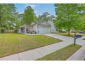 Single-story home with manicured lawn, mature trees, and a driveway leading to an attached garage at 2427 Stingray Blvd, North Charleston, SC 29406