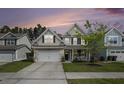 Charming two-story home with a well-maintained lawn, a two-car garage, and a cozy front porch at dusk at 317 Whispering Breeze Ln, Summerville, SC 29486