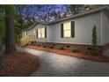Charming single story home at dusk featuring a gravel yard and red brick accents, nestled in a wooded area at 409 Peacock Ln, Summerville, SC 29483