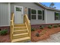 Close up of the home's entrance and front porch with wooden steps, red brick accents, and a freshly landscaped front yard at 409 Peacock Ln, Summerville, SC 29483
