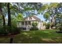 Spacious back yard featuring a charming home with a porch, surrounded by mature trees and lush greenery at 8374 Chisolm Plantation Rd, Edisto Island, SC 29438