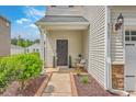 Charming front porch with a dark-colored door, side table, plants, and tasteful landscaping at 9707 Seed St, Ladson, SC 29456