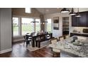 Sunlit dining area featuring dark wood table and bench with large windows overlooking a green landscape at 100 Fish Rd, Ridgeville, SC 29472