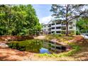 Exterior view of the building with a pond and lush greenery in a serene community at 1025 Riverland Woods Pl # 106, Charleston, SC 29412
