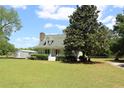 White two-story home with mature landscaping, featuring a large tree and storage shed at 18808 Round O Rd, Round O, SC 29474