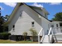 The side of this beautiful two-story home features white siding, a back deck, and manicured landscaping at 18808 Round O Rd, Round O, SC 29474