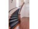 Elegant staircase with dark carpet, hardwood floors, and a curved railing with classic design at 192 Ashley Ave # C, Charleston, SC 29403