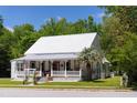 Inviting two story home with a metal roof, classic design, and a cozy front porch surrounded by lush greenery at 21785 Lowcountry Hwy, Ruffin, SC 29475
