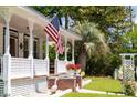 Charming front porch featuring classic white railings, a decorative pergola, and an American flag waving at 21785 Lowcountry Hwy, Ruffin, SC 29475