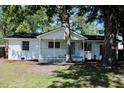 Exterior view of the freshly painted white brick home, complete with a charming covered porch and mature trees at 227 Amy Dr, Goose Creek, SC 29445