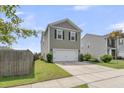 View of the two-story home with an attached two-car garage, set in a fenced backyard at 9706 Fanning Basket Ln, Ladson, SC 29456