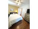 Bedroom featuring hardwood floors, ceiling fan, closet access, and geometric patterned wall at 1159 Camden St, North Charleston, SC 29405