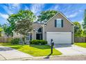 Charming single-Gathering home featuring a well-manicured lawn, lush landscaping, and a two-car garage at 129 Mockernut Dr, Ladson, SC 29456
