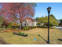 Spacious front lawn with mature landscaping and a view of the two-story home at 1511 Fairway Dr, Charleston, SC 29412