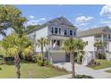 Stunning two-story coastal home featuring a charming front porch, driveway, and lush palm trees at 1513 Cultivation Ln, Mount Pleasant, SC 29466